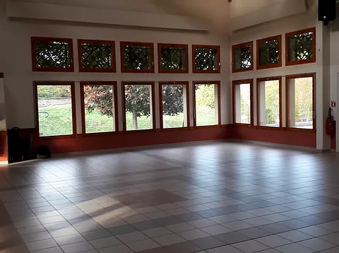 Salle collective à Plan, parquet et fenêtres sur la verdure